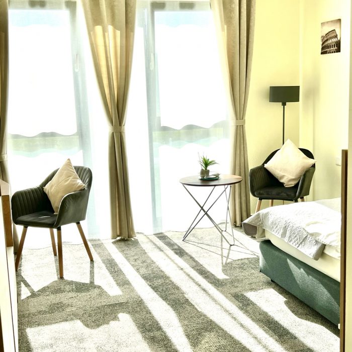 LikeDaheim 1-Zimmer Apartment Ansicht mit Sitzecke und Bett, viel natürliches Licht